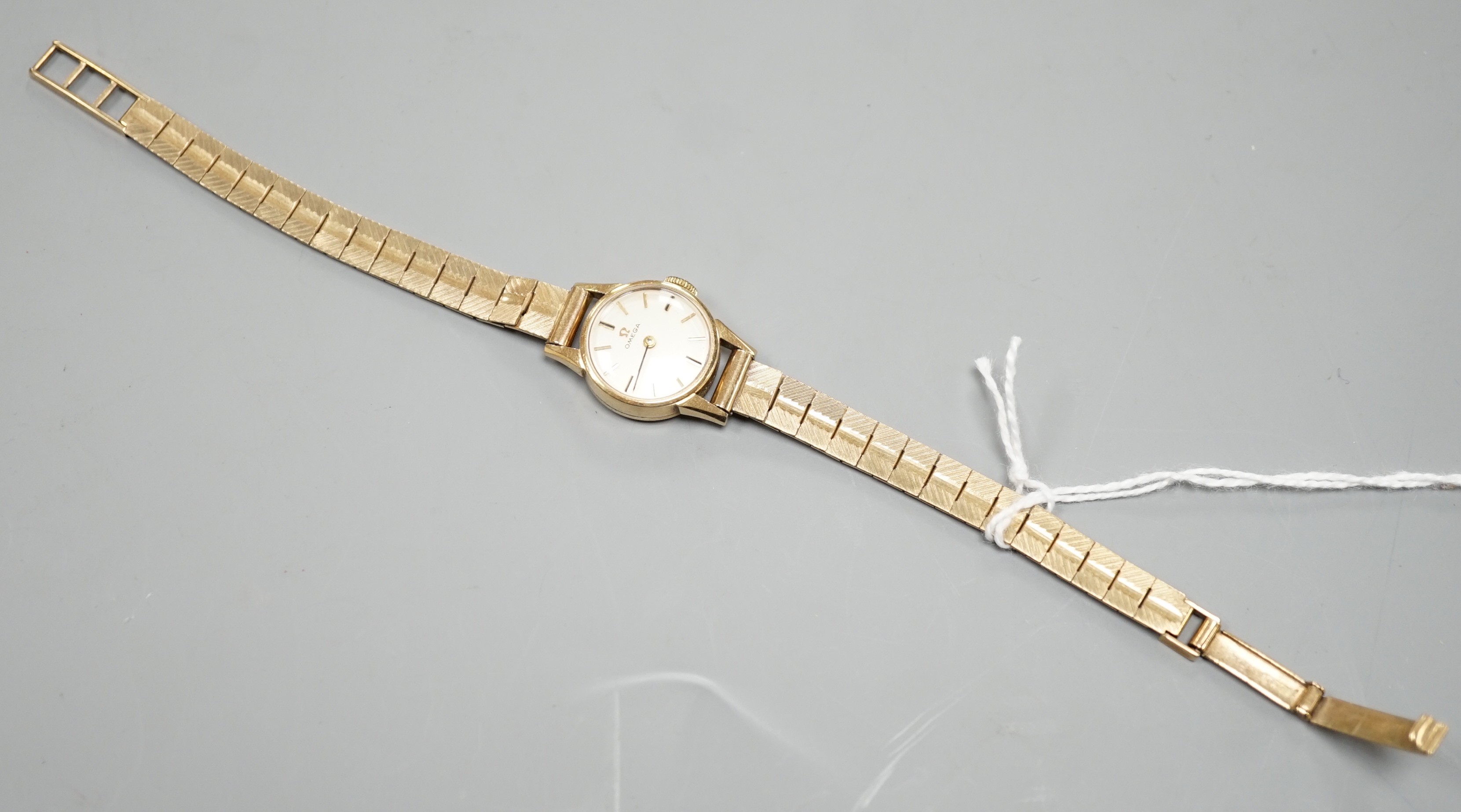 A lady's 9ct Omega manual wind wrist watch, on a 9ct gold bracelet